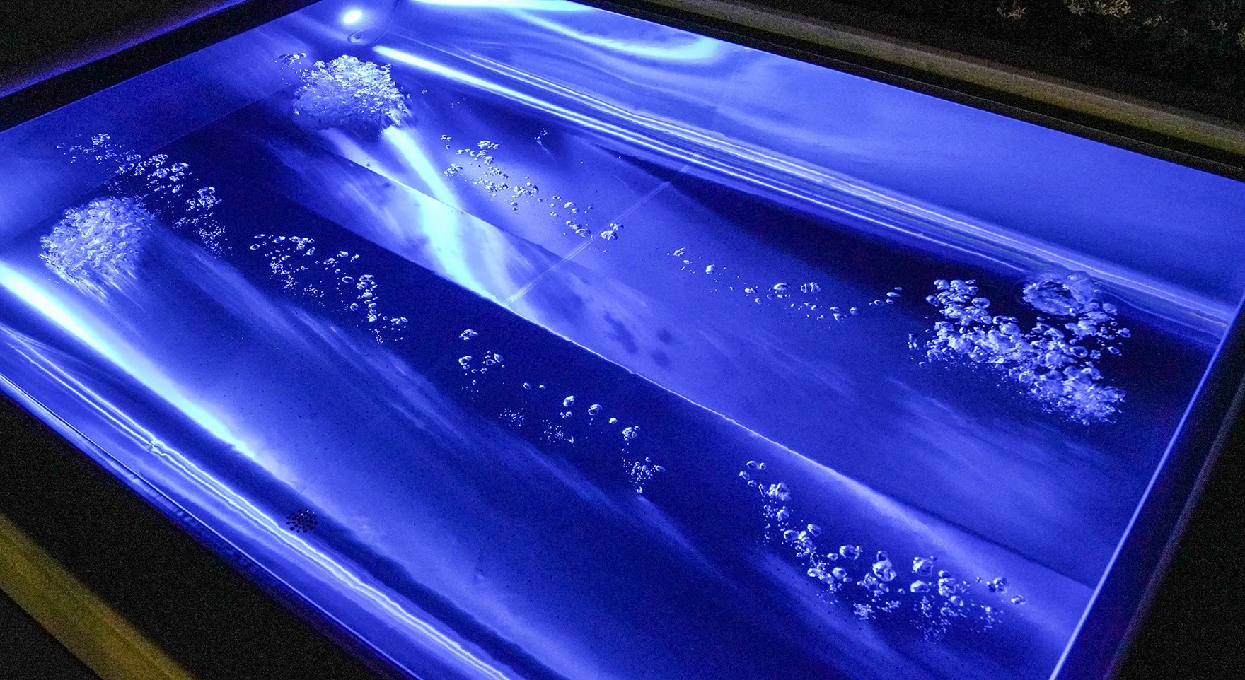 Eau éclairée en bleu dans un bassin en acier inox