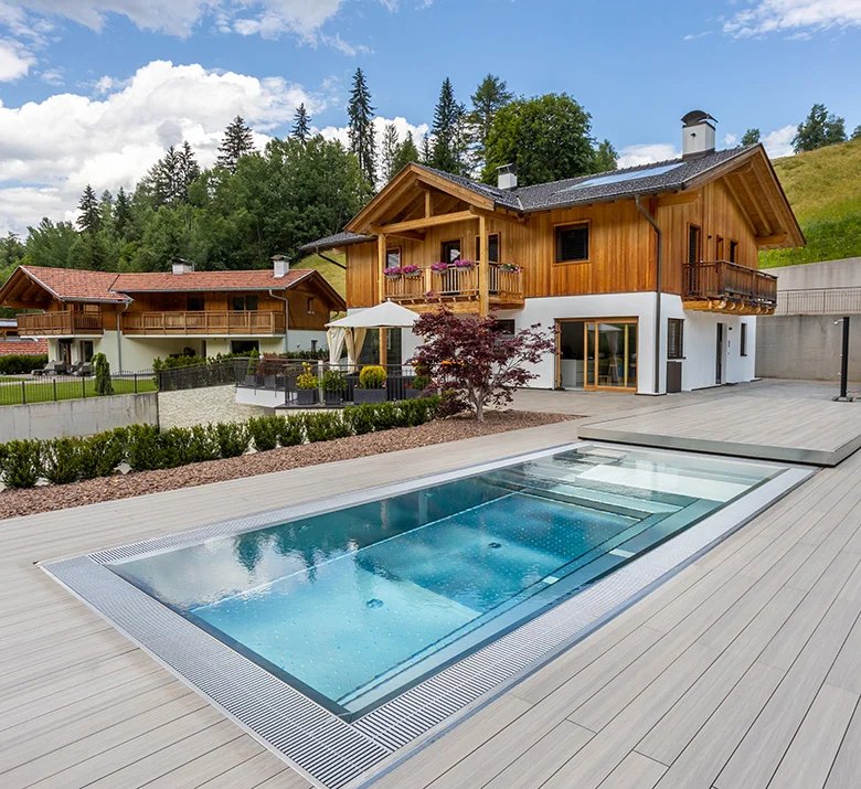 Piscine en acier inox H2O Style sur une terrasse en bois, devant un chalet