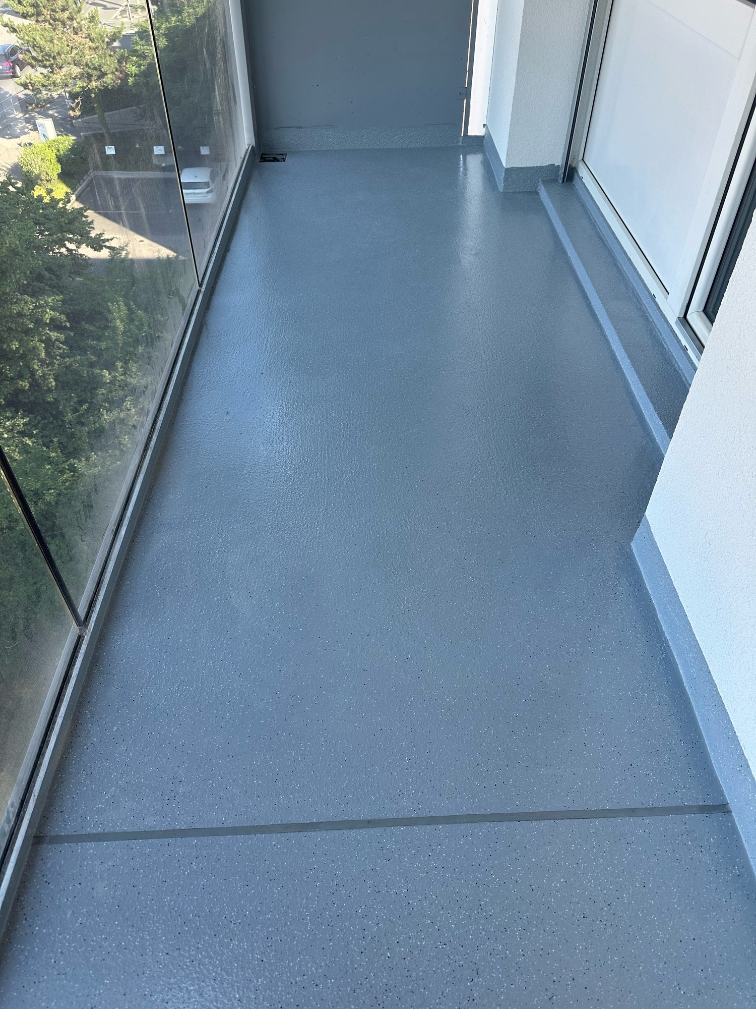Grey resin walkway along a glass balustrade