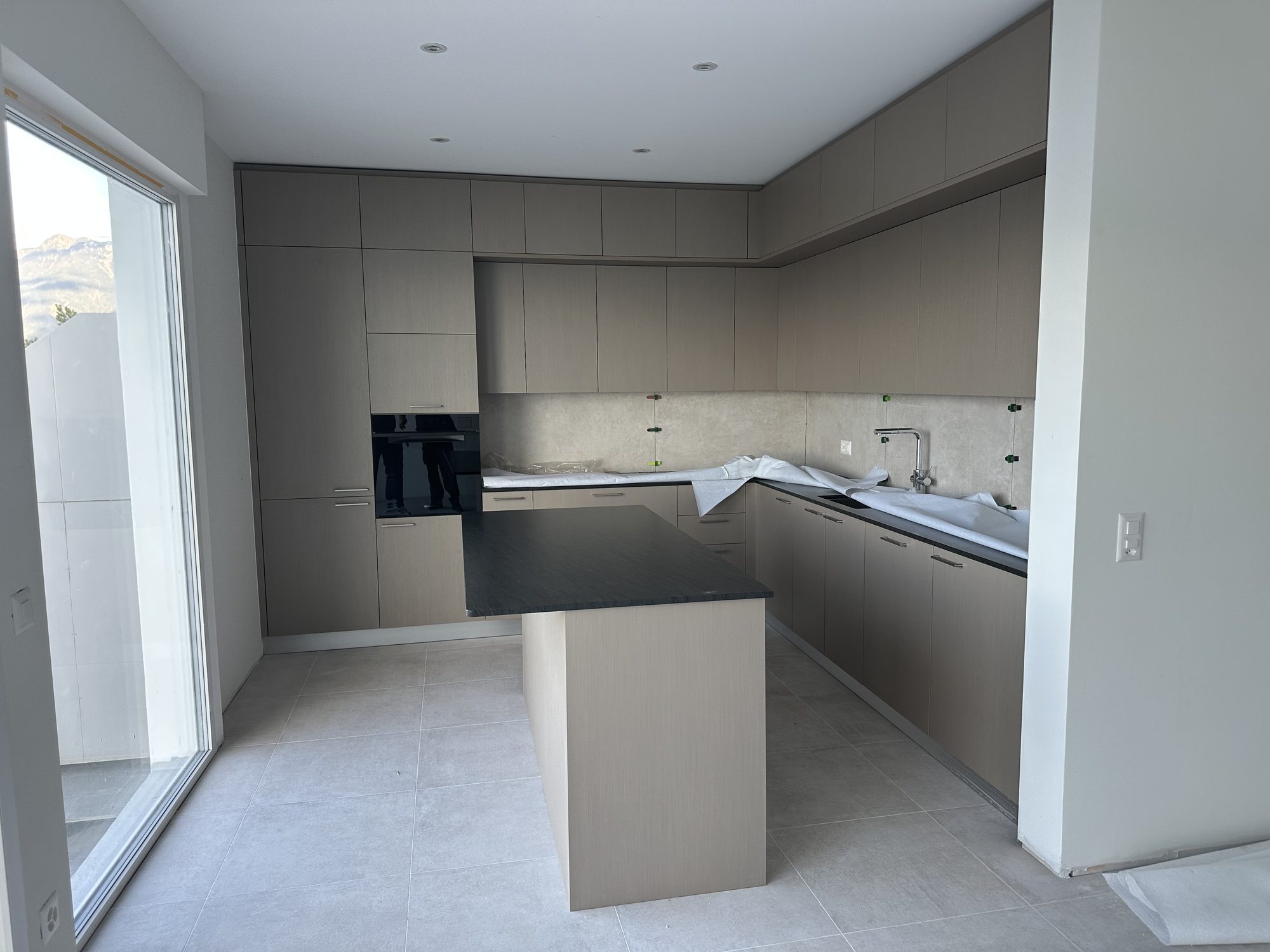 Taupe kitchen with a black-topped island, overall view