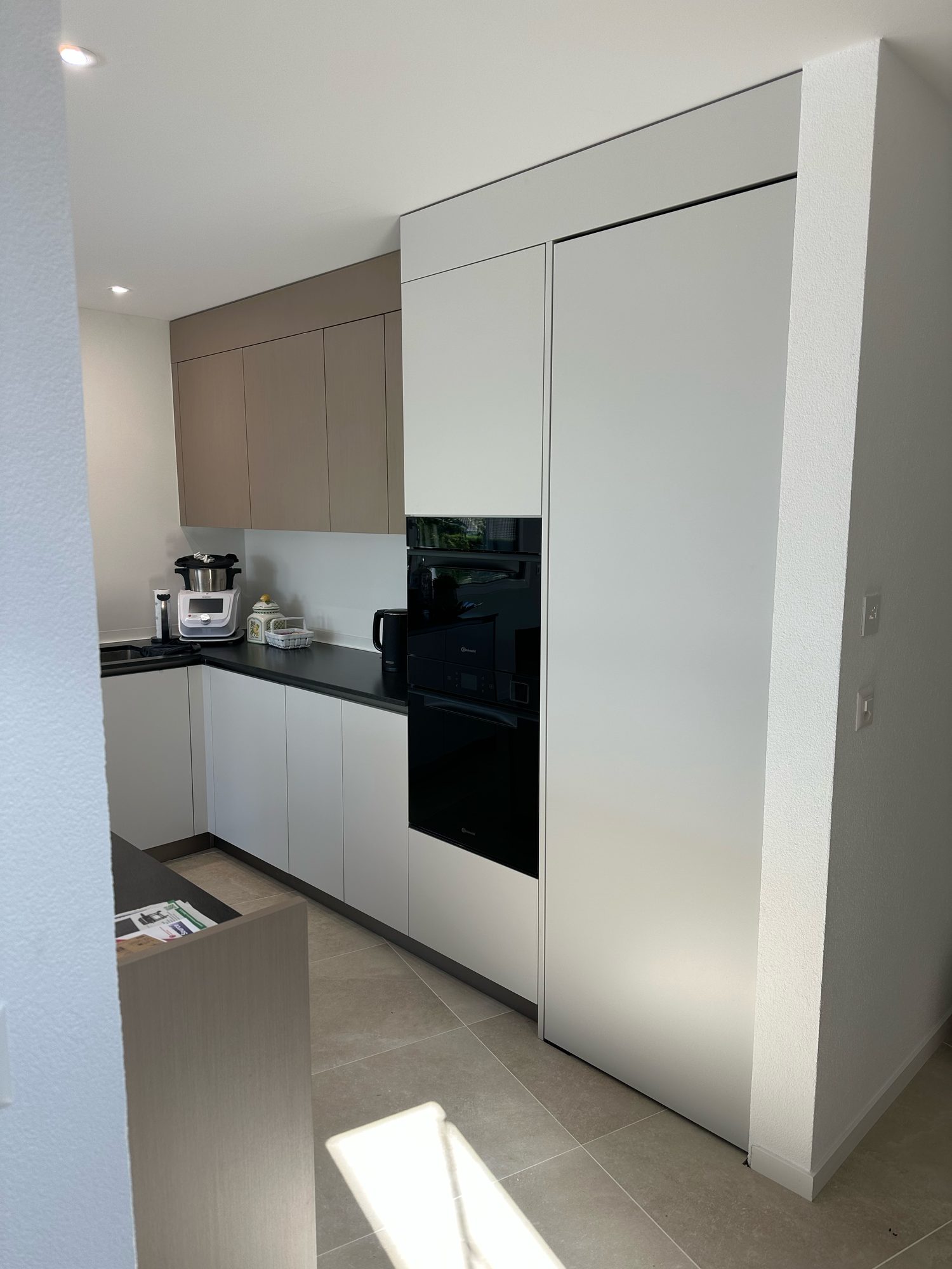 White tall unit with built-in oven and L-shaped return