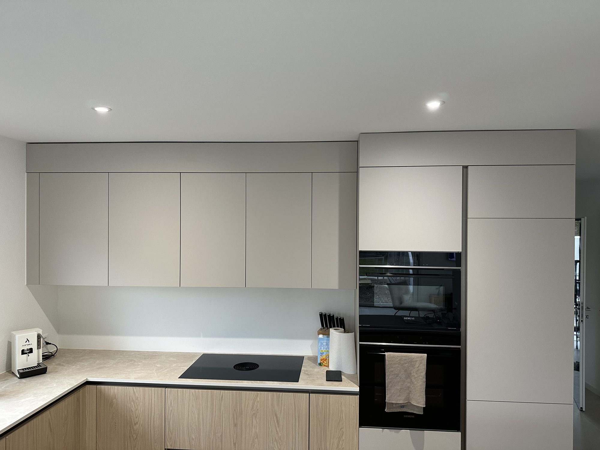 Light grey and wood kitchen with two ovens in a tall unit