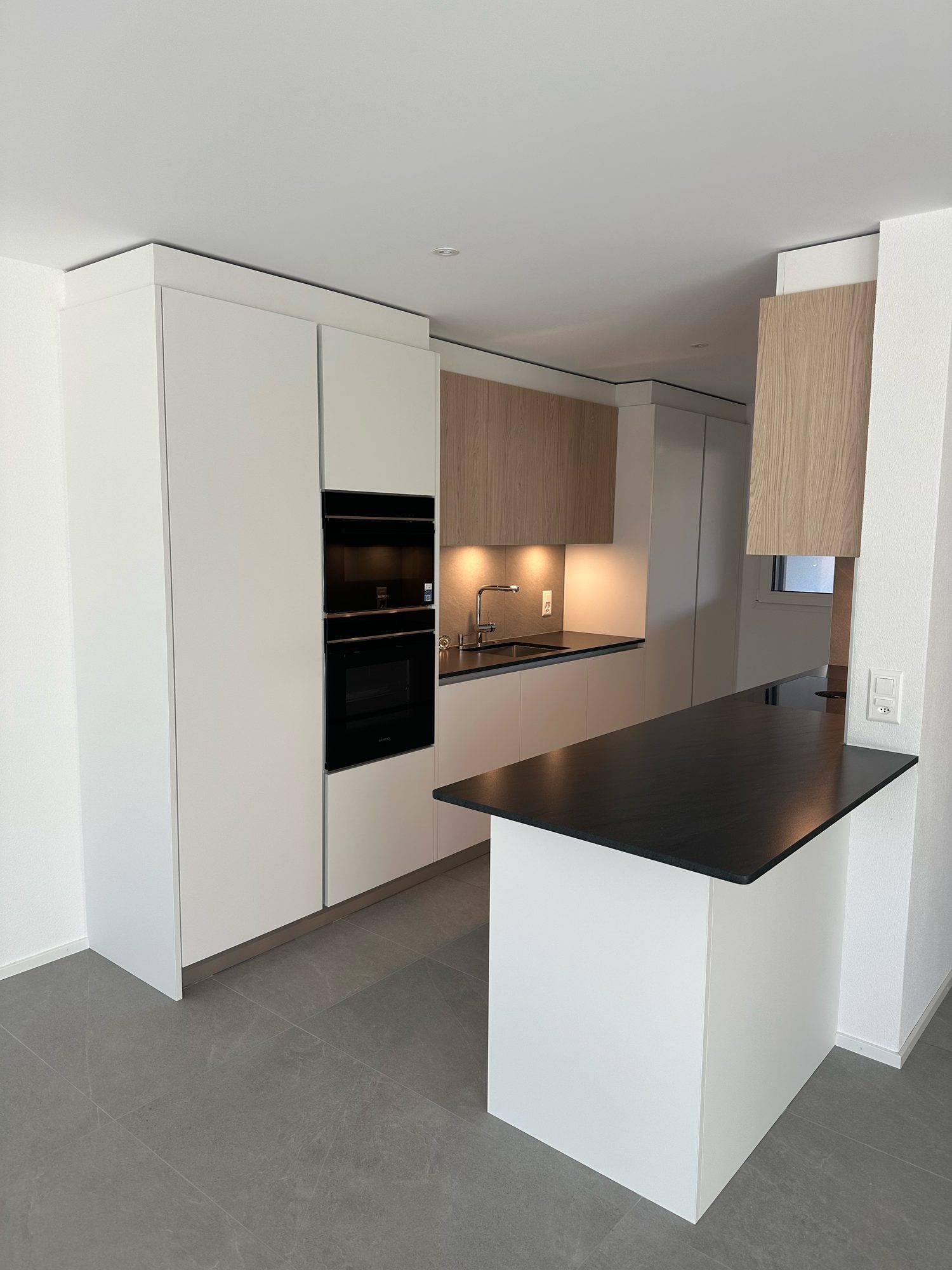 White kitchen with a peninsula and black worktop