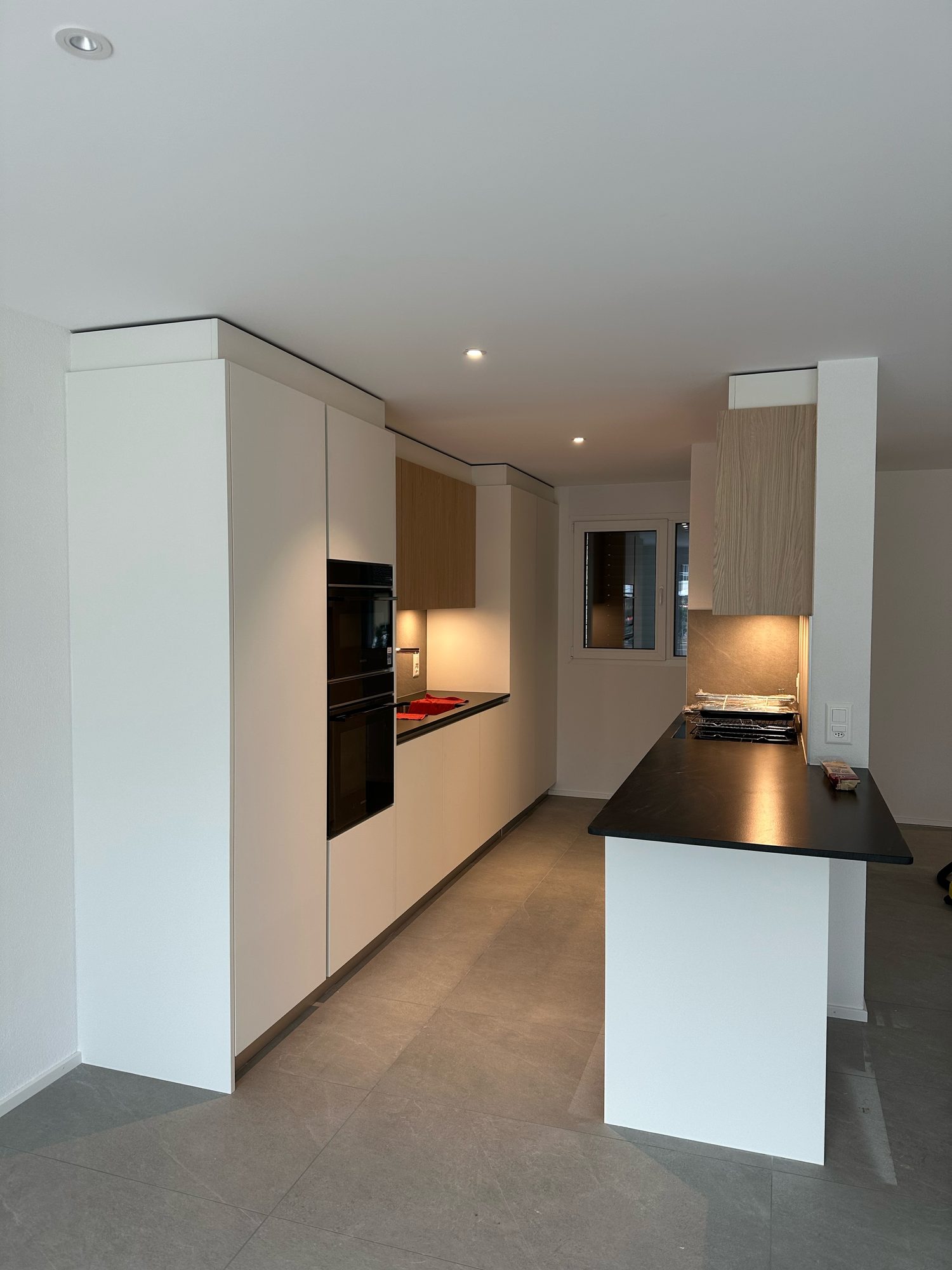 White tall units, lit wooden niche and peninsula