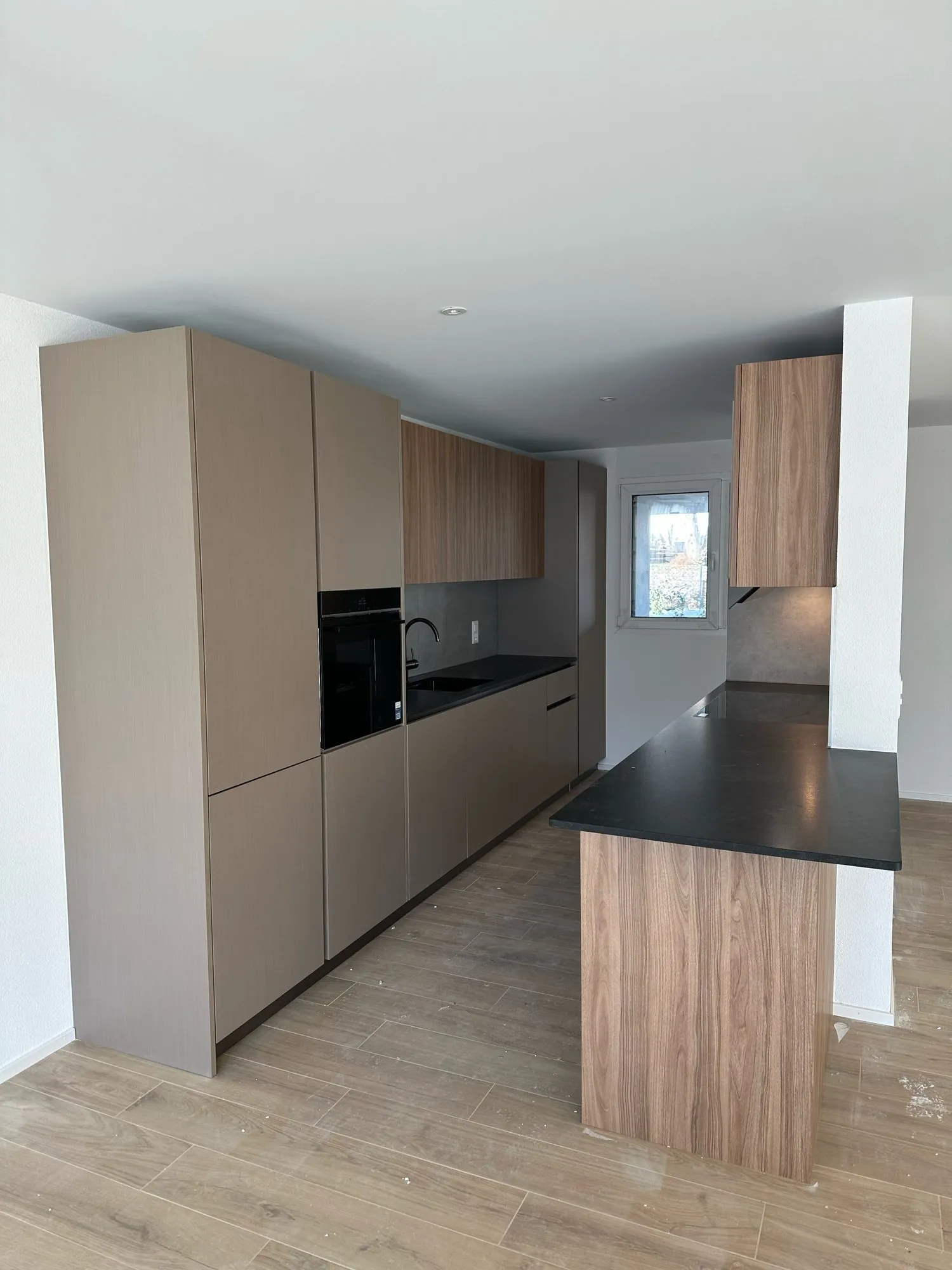 Taupefarbene Küche mit holzfurnierter Insel, Gesamtansicht