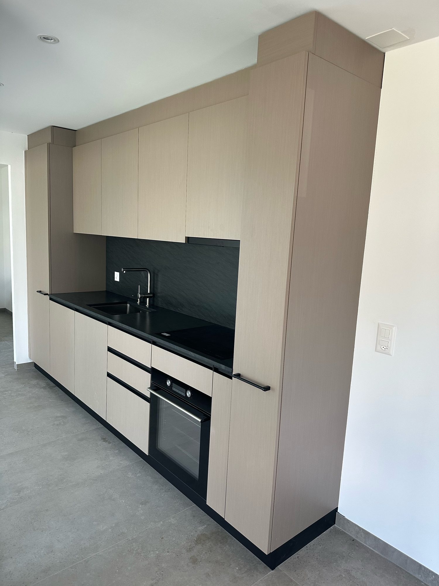 Taupe single-wall kitchen with black splashback