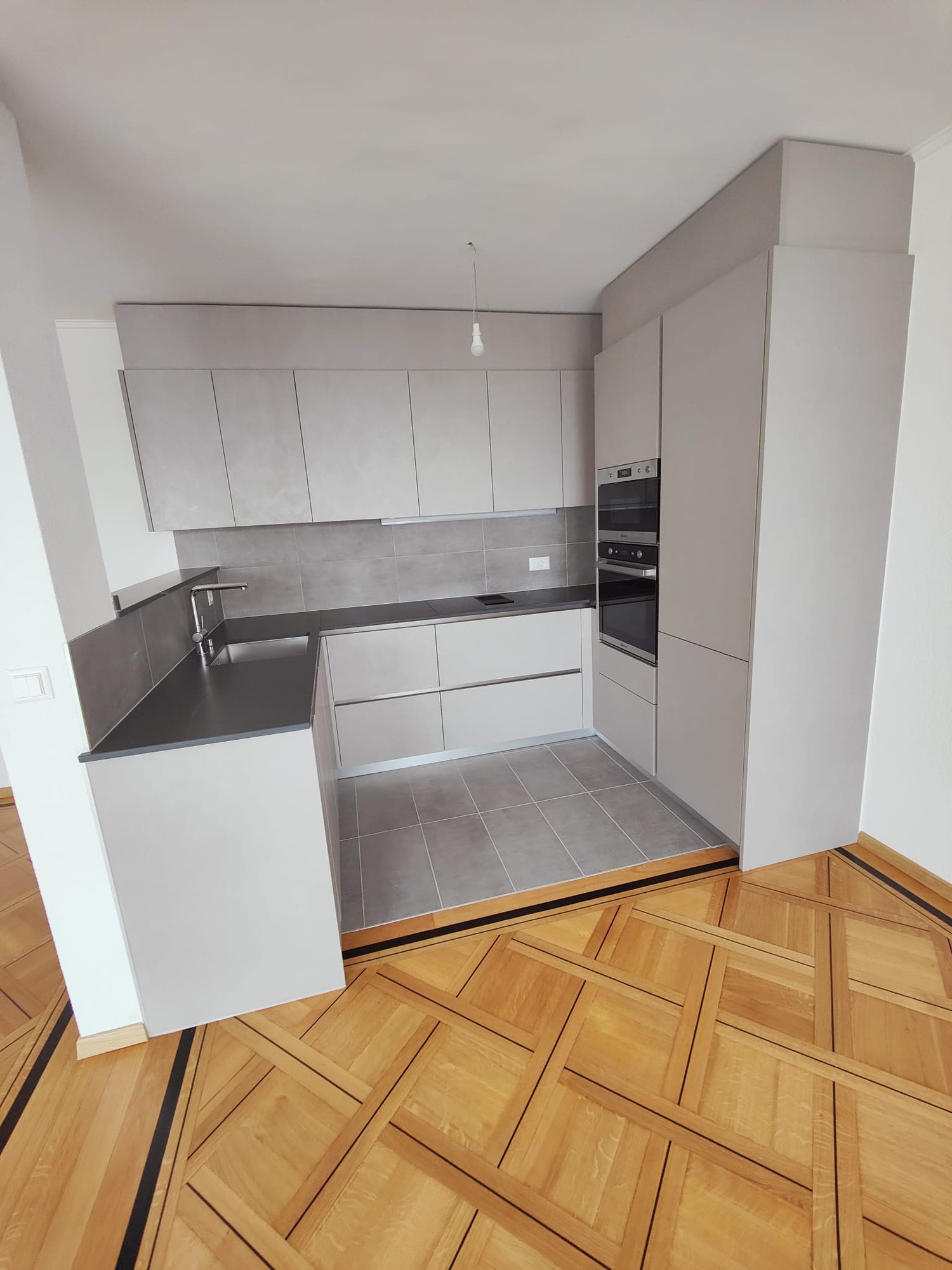Finished grey U-shaped kitchen on patterned parquet