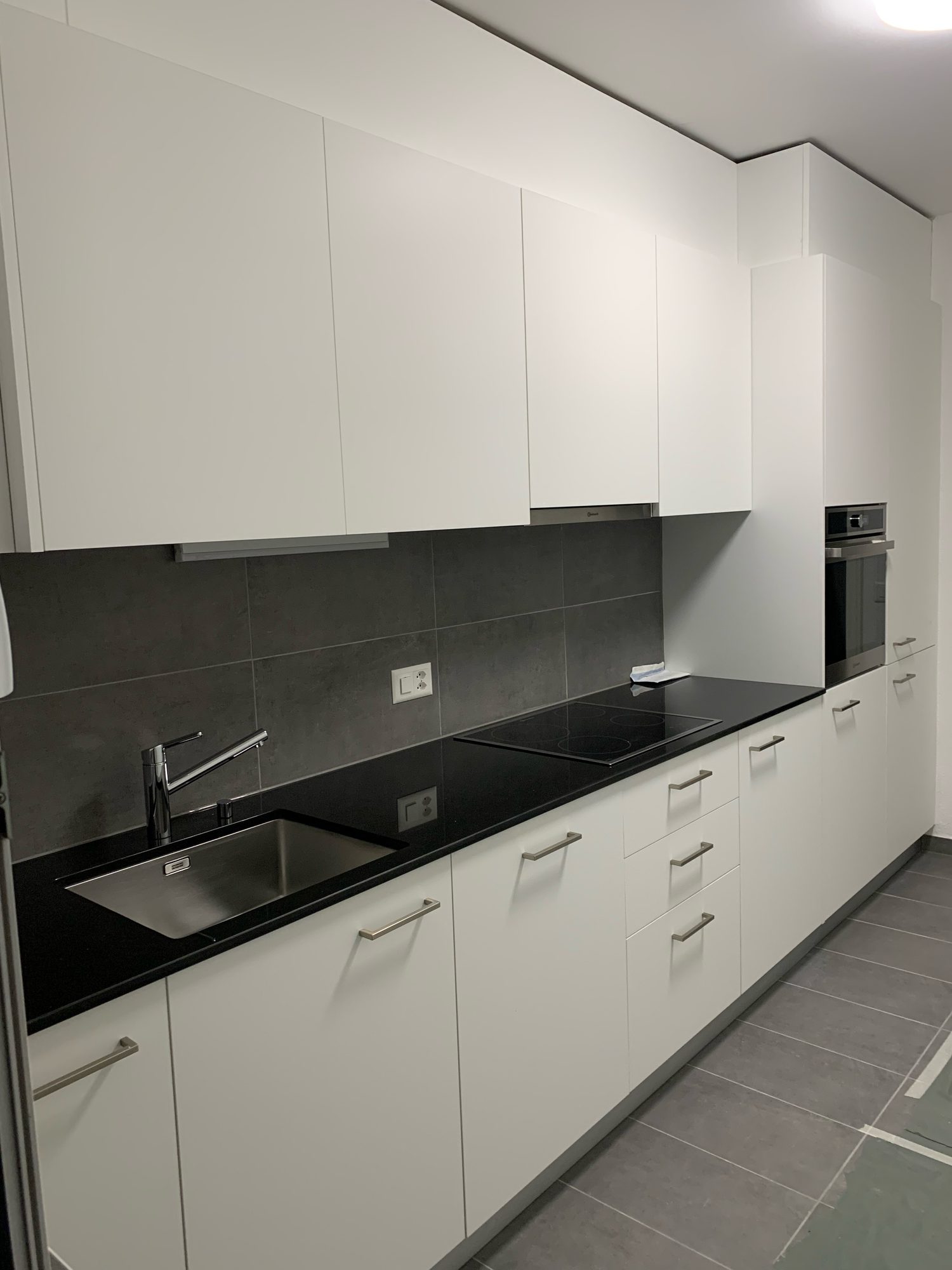 White kitchen with black top and grey splashback