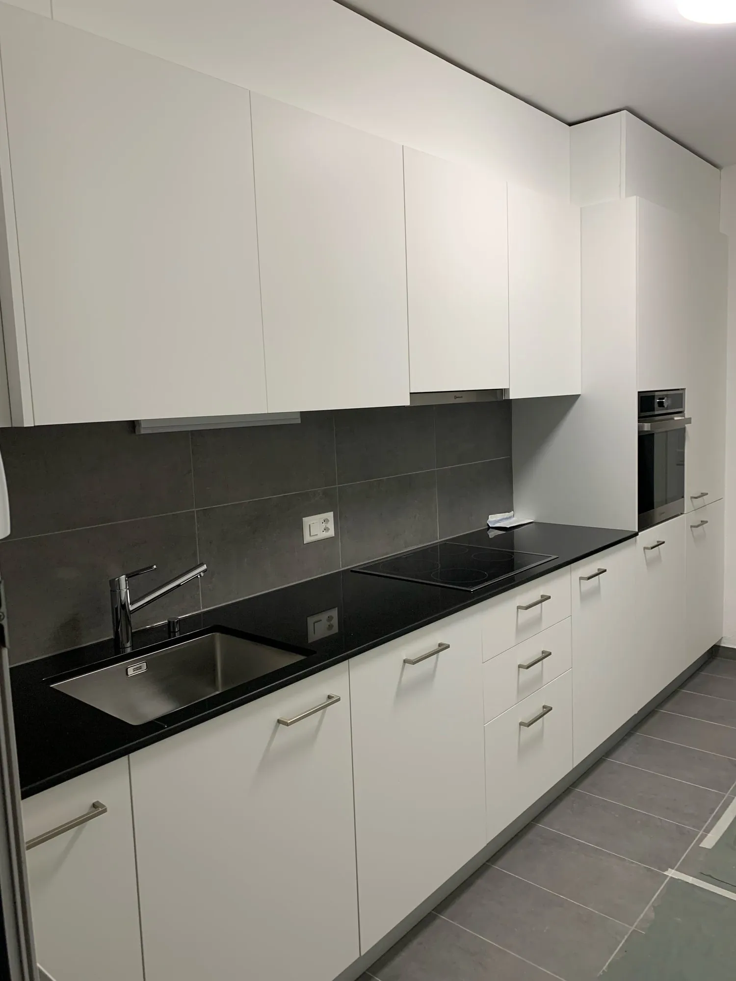 Weisse Küche mit schwarzer Platte und grauer Rückwand