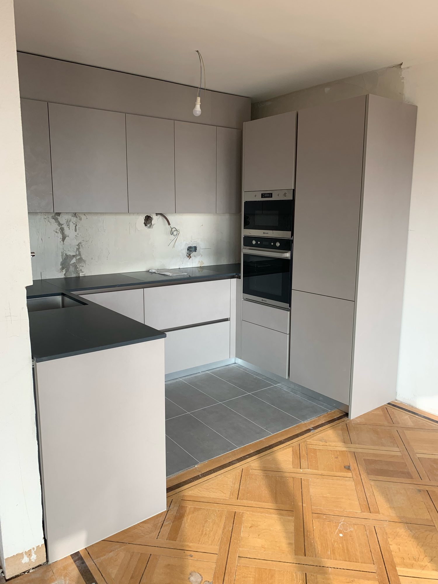 Grey U-shaped kitchen during installation