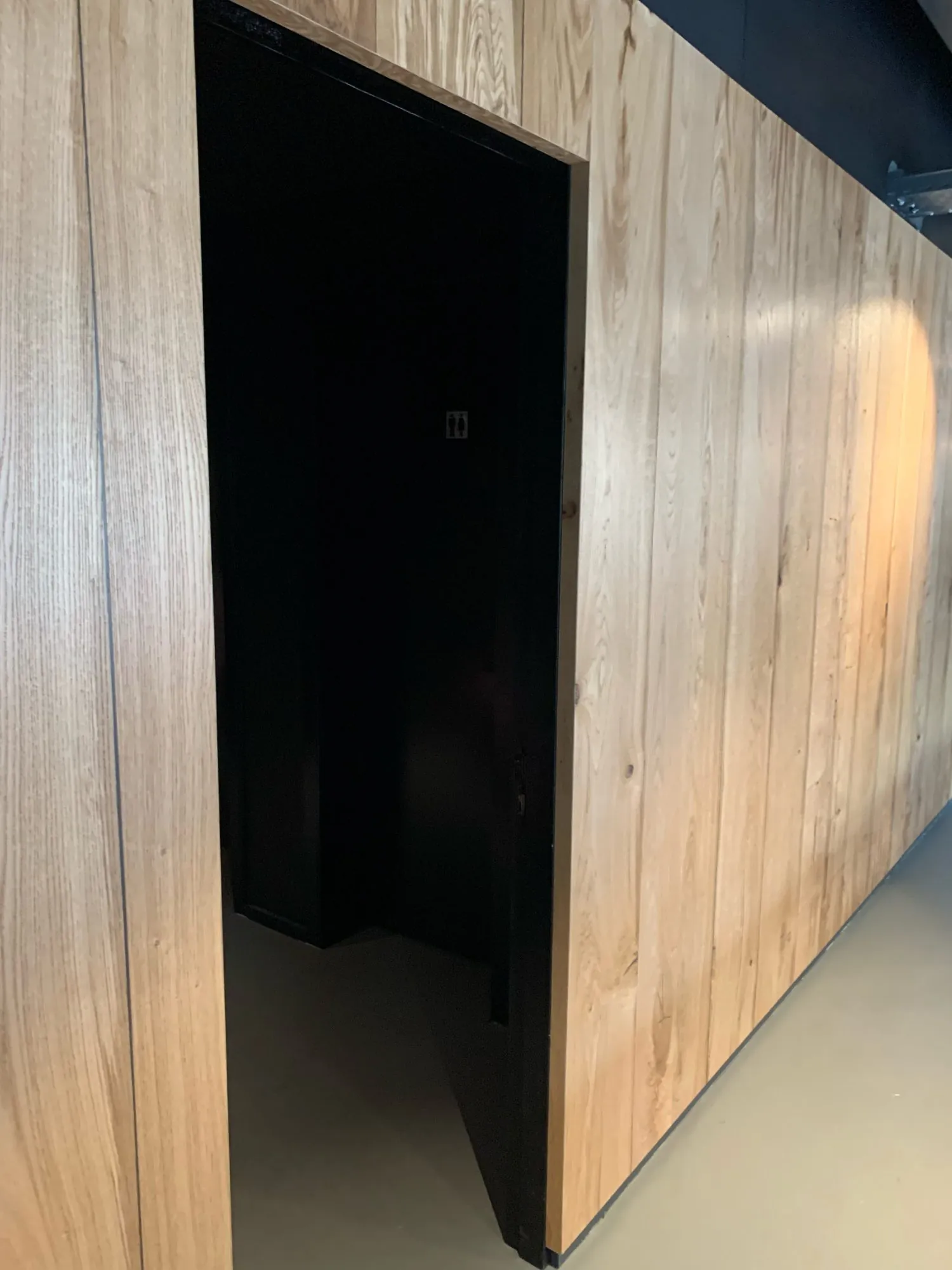 In die Holzverkleidung integrierte schwarze Tür