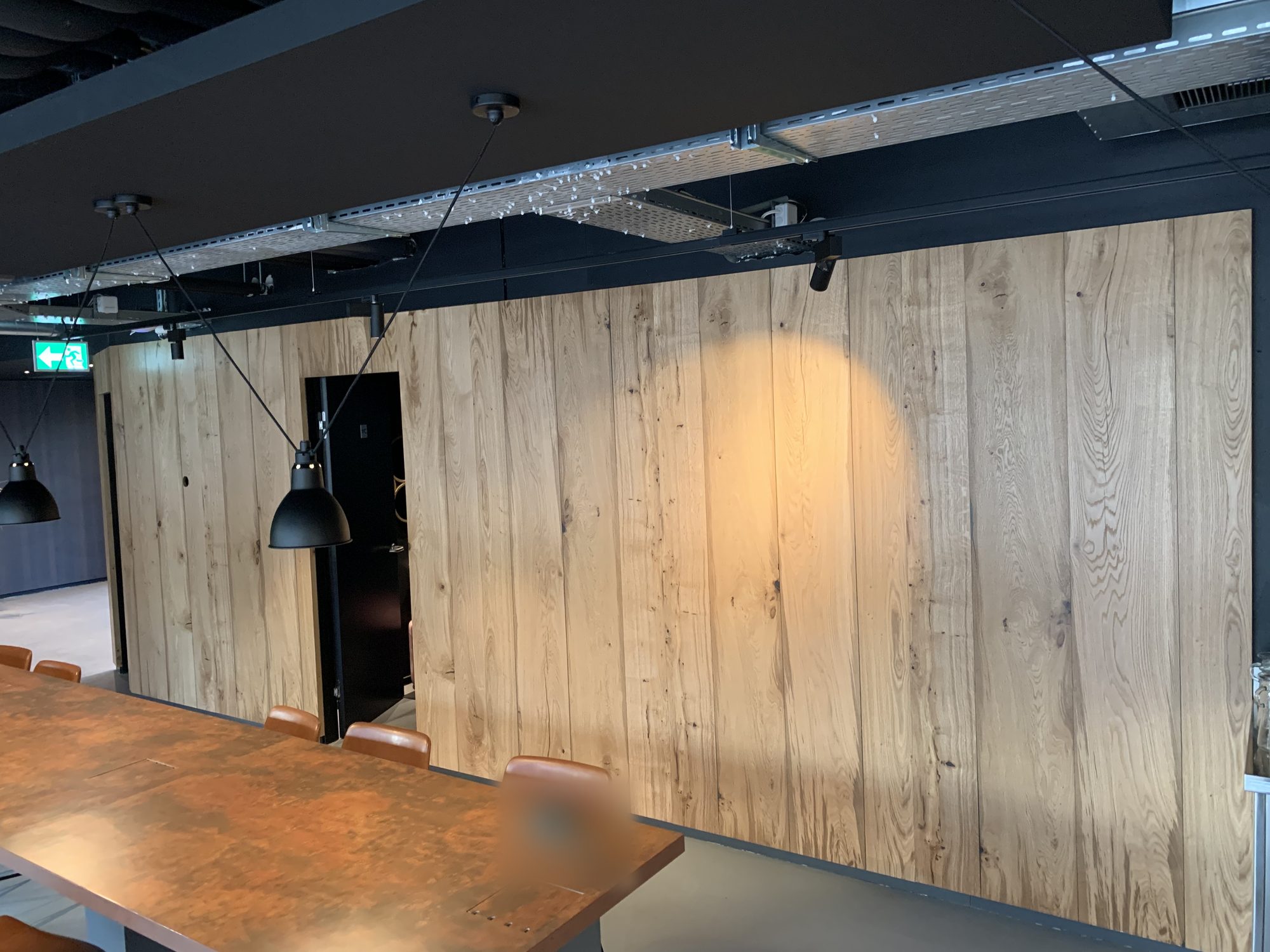 Large wall of light wood panels under a black ceiling