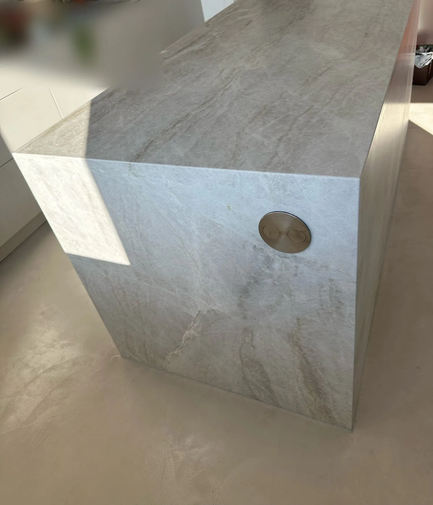 Mit grauem, geädertem Stein verkleidete Kochinsel