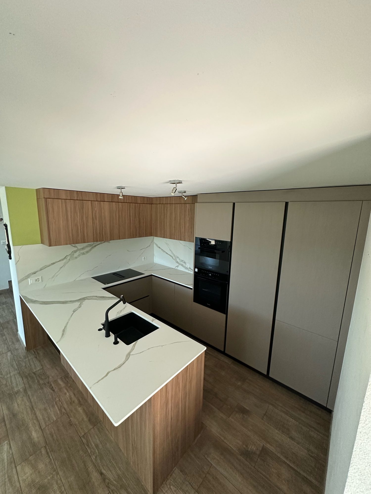 Marble-look peninsula and tall units of the new kitchen