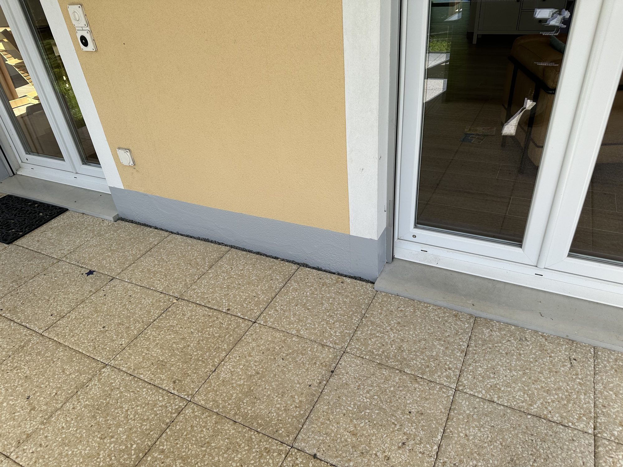 Grey coating at the base of the façade, along the paving