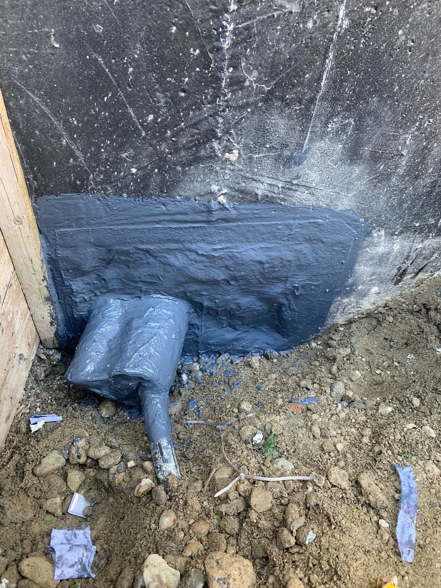 Blue waterproofing at the foot of a wall, around a pipe